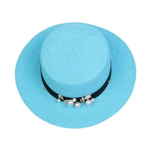 Close-up of light blue straw boater hat with black ribbon, pearls and floral accents