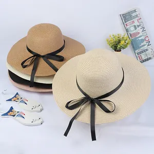 Detailed view of woven straw sun hats in multiple colors with black ribbon bow tie