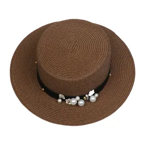 Detail view of woven brown straw hat with elegant pearls and silver flower decorations