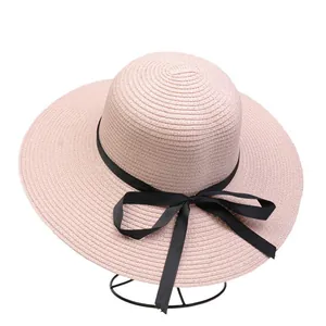 Detailed macro view of the fine straw weave and black ribbon bow on a pink sun hat