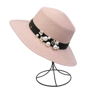 Detailed texture of pink straw sun hat with elegant pearl and floral decorations