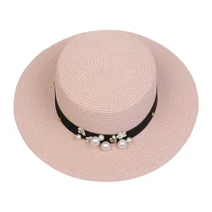 Detailed macro of pink straw boater hat with black ribbon, pearls and floral accents