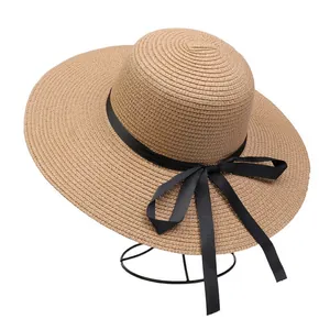 Detail of wide brim straw sun hat with elegant black ribbon bow on a display stand