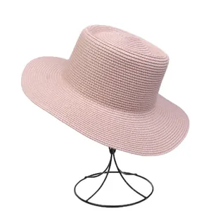 Detail of light pink flat top straw hat with fine woven texture and sun protection brim