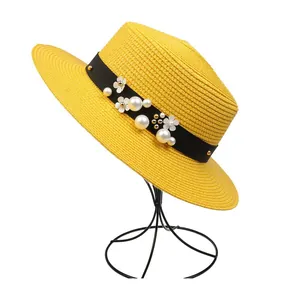 Detail of yellow woven straw hat featuring black ribbon with pearl and floral ornaments
