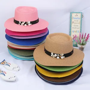 Close-up of woven straw boater hats with elegant pearl and floral ribbon decorations