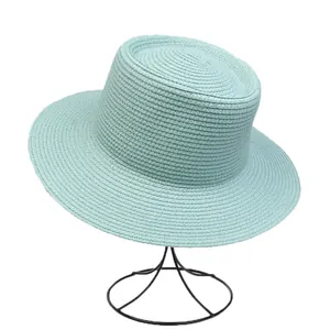 Detail of mint green straw hat weave on a black stand against a white background