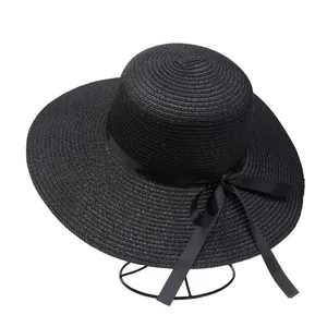 Close-up of black straw sun hat featuring a wide brim and decorative satin ribbon bow