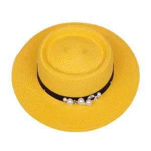 Detail of yellow straw hat with black ribbon, white pearls and floral decorations