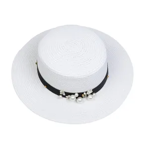 Detail of white boater hat with black ribbon, elegant pearls and small flower decorations