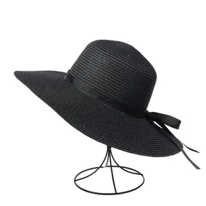 Detail of a black wide-brim straw sun hat with an elegant satin ribbon bow on a stand