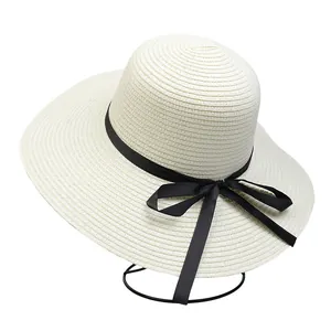Detail shot of beige straw hat with black ribbon bow and fine woven texture