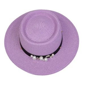 Close-up of pearl flower ornaments and black ribbon on a purple straw boater hat
