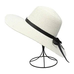 Detail of a beige woven sun hat featuring a black ribbon bow on a display stand