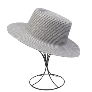 Detailed close-up of grey woven flat top straw hat on a minimalist black metal stand