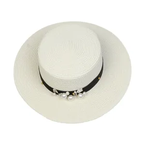 Close-up of white boater hat with black ribbon, pearls, and small floral accents