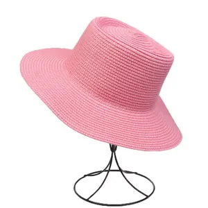 Detail of pink straw boater hat with fine woven texture on a metal display stand