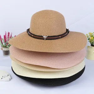 Detail of woven straw hats featuring leather bands with metal bull head charms