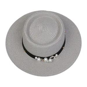 Close-up of woven straw hat with black ribbon, white pearls and floral ornaments
