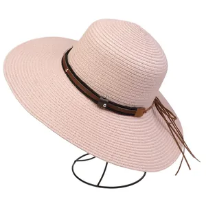 Detail of pink straw sun hat featuring a brown studded leather band with long tassels