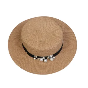 Close-up of woven straw hat featuring black ribbon with pearls and flower details