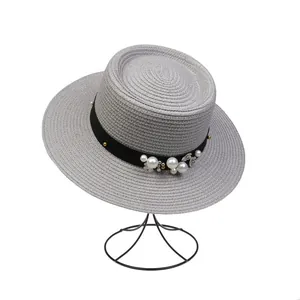 Detail of grey straw boater hat with pearl, floral accents and black decorative band