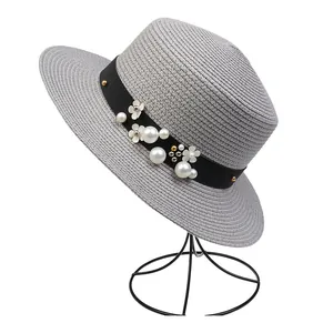 Detailed view of grey straw sun hat with black ribbon, white pearls, and floral accents