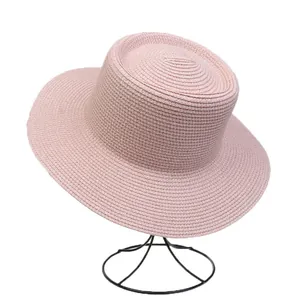 Close-up of pink straw hat with wide brim on metal stand for summer beach sun protection