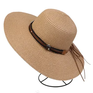 Detail of wide brim straw hat with brown leather belt and metallic rivet accents