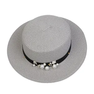 Close-up of elegant grey straw hat with pearl and flower ornaments on black band