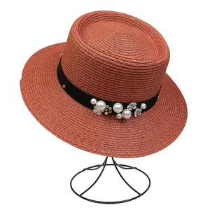 Detail of red straw sun hat featuring elegant pearls and white flower ornaments