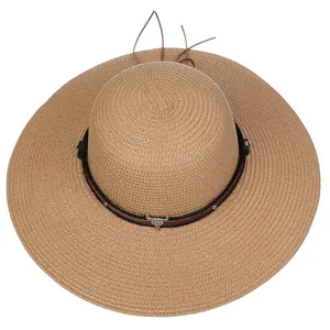 Close-up of wide brim straw hat with brown band, metal rivets and bull head pendant