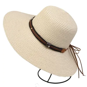 Detail of wide brim straw sun hat with leather decorative band and silver metal rivets