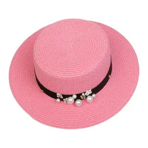 Close-up of pink boater hat with black ribbon, white pearls and floral decorations