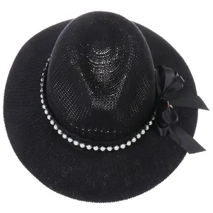 Close-up of black woven fedora hat featuring white pearls and a silk bow decoration