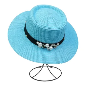 Close-up of blue straw hat with black ribbon, pearl accents and small silver flowers
