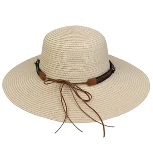 Detail of beige straw hat with woven texture and decorative brown leather band tie