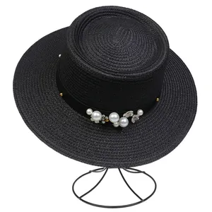Detailed view of black boater hat with elegant pearl and floral ribbon decoration