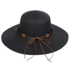 Detail of black woven wide brim sun hat featuring brown leather ribbon and metal studs