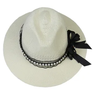 Detail of cream straw hat with black lace, white pearls and large satin ribbon bow