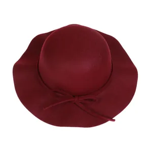 Close-up of elegant burgundy wool felt hat with wavy wide brim and bow detail