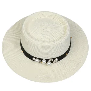 Detail of the woven straw hat featuring black ribbon with pearls and flower accents