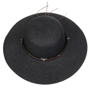Detail of black straw beach hat with leather band and metal ox head buckle ornament