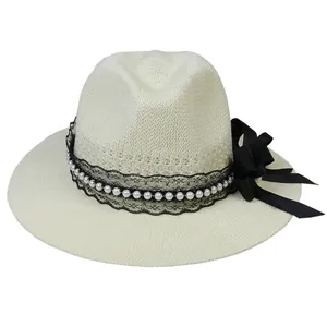 Detail of summer straw hat with black lace trim, pearl accents and a decorative bow