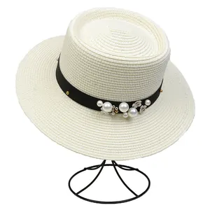 Detailed view of white boater hat with black ribbon, pearl accents, and floral decor