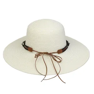 Detailed view of wide brim straw hat with brown ribbon bow and metallic rivet detail