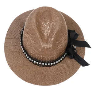 Close-up of woven straw fedora featuring black lace ribbon and elegant pearl embellishments