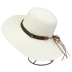 Detail of cream woven sun hat with studded leather band and long decorative tassels