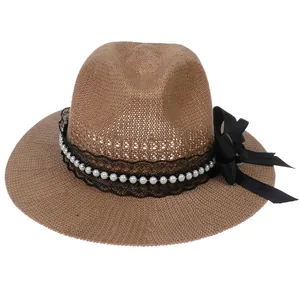Detail of natural brown straw hat with black lace, white pearls and a large satin bow