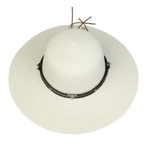 Detail of wide brim straw hat with leather strap and silver bull head metal accessory
